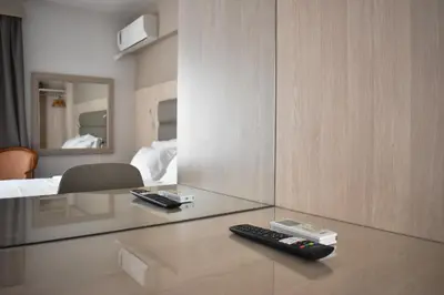 a room with two remote controls on a glass table at Anemoni Piraeus Hotel in Piraeus