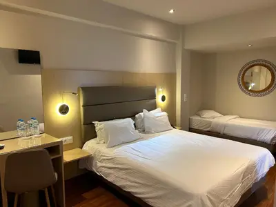 a bedroom with two beds and a desk and a mirror at Anemoni Piraeus Hotel in Piraeus