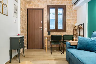 a living room with a blue couch and a wooden door at Cute tiny apartment in the heart of Flisvos in Athens