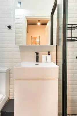 a white bathroom with a sink and a mirror at Cute tiny apartment in the heart of Flisvos in Athens