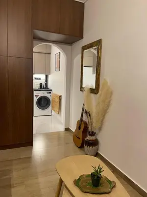 a living room with a table and a guitar at Cute tiny apartment in the heart of Flisvos in Athens