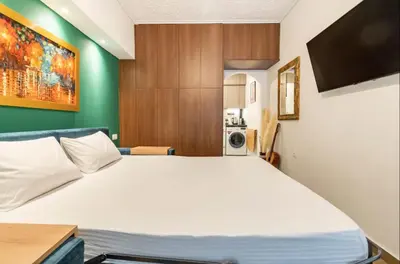 a bedroom with a large white bed and a green wall at Cute tiny apartment in the heart of Flisvos in Athens