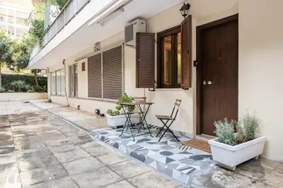 a patio with a table and chairs in front of a house at Cute tiny apartment in the heart of Flisvos in Athens