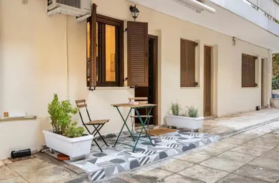a patio with a table and chairs and a building at Cute tiny apartment in the heart of Flisvos in Athens