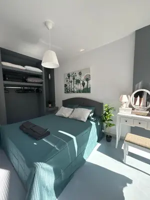 a bedroom with a blue bed and a mirror at Sea Urban 4 Varkiza in Vari