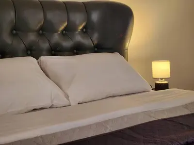 a bed with a black leather headboard and a lamp at Comfy Place In Panteleymon VIPGreece in Athens