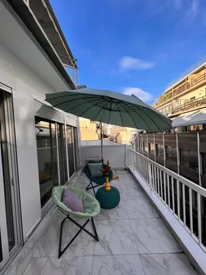 a patio with two chairs and an umbrella on a balcony at Casa de Tres Hermanos in the heart of Athens in Athens