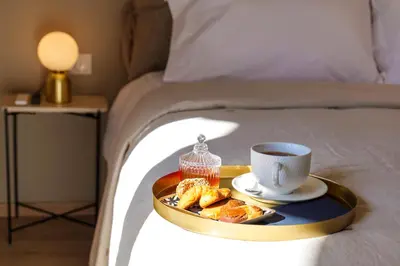 a tray with a cup of coffee and pastries on a bed at Acropolis Deluxe 2BR Apartment in Athens