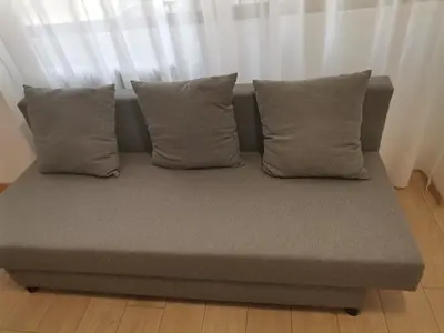 a couch with four pillows on a wooden floor at S & K Apartment free indoor parking in Athens