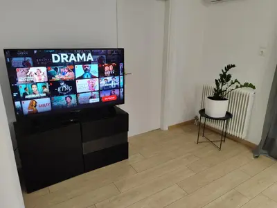 a flat screen tv sitting on a stand in a room at S & K Apartment free indoor parking in Athens