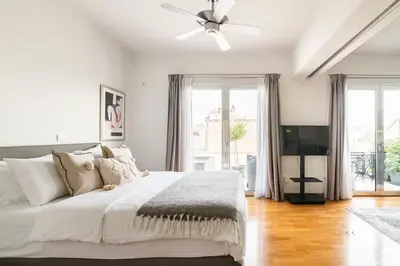 a white bedroom with a bed and a ceiling fan at Heated Plunge Pool & Firepit Acropolis Penthouse in Athens