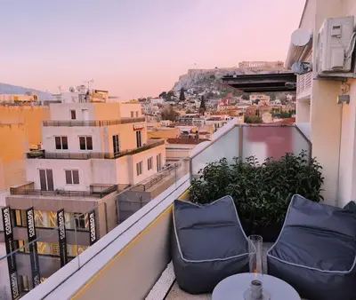 a balcony with two chairs and a view of a city at Heated Plunge Pool & Firepit Acropolis Penthouse in Athens