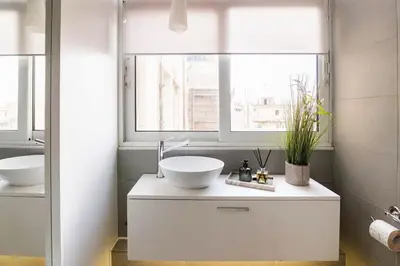 a white bathroom with a sink and a window at Heated Plunge Pool & Firepit Acropolis Penthouse in Athens