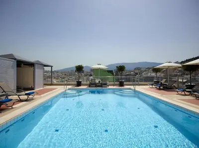 a large swimming pool with chairs and umbrellas at Athens Zafolia Hotel in Athens