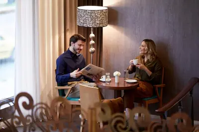 a man and woman sitting at a table in a restaurant at Athens Zafolia Hotel in Athens