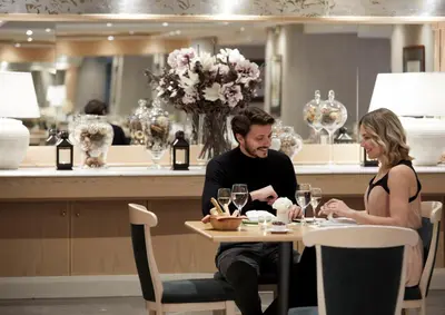 a man and woman sitting at a table with wine glasses at Athens Zafolia Hotel in Athens