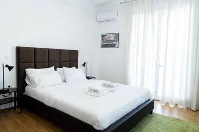 a bedroom with a large white bed with a black headboard at Comfort Sunny Hub with 2 bdr in Athens
