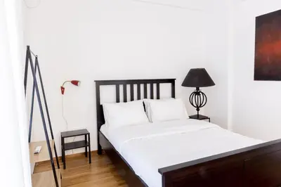 a bedroom with a bed with white sheets and a lamp at Comfort Sunny Hub with 2 bdr in Athens