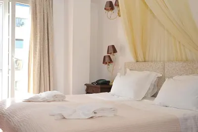 a bedroom with a bed with white sheets and a window at Acropolis Museum Boutique Hotel in Athens