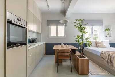 a bedroom with a bed and a table and a kitchen at Premium Apartments in Paleo Faliro by UPSTREET in Athens