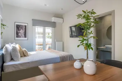 a bedroom with a bed and a table with a plant at Premium Apartments in Paleo Faliro by UPSTREET in Athens