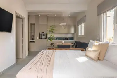 a large white bed in a room with a kitchen at Premium Apartments in Paleo Faliro by UPSTREET in Athens