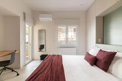 a bedroom with a bed and a desk and windows at Premium Apartments in Paleo Faliro by UPSTREET in Athens