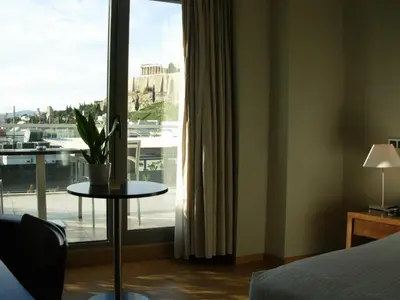 a hotel room with a large window and a table with a plant at The Athens Gate Hotel in Athens