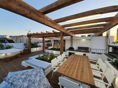 an outdoor patio with a wooden table and white chairs at Athens Hill Suite in Athens
