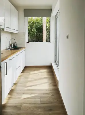 a kitchen with white cabinets and a large window at Athens Hill Suite in Athens