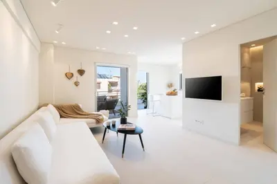 a white living room with a white couch and a tv at 2BD Boho Sea View Apartment by The Olon in Vari