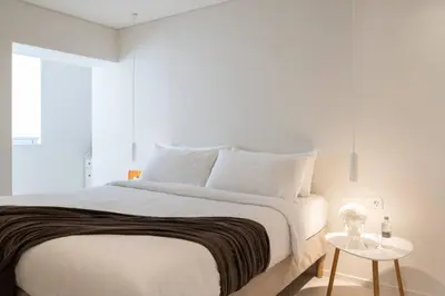 a bedroom with a large white bed with a table at 2BD Boho Sea View Apartment by The Olon in Vari