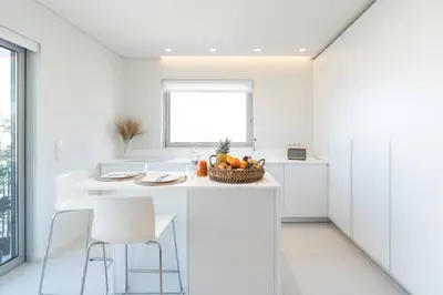 a white kitchen with a bowl of fruit on a counter at 2BD Boho Sea View Apartment by The Olon in Vari