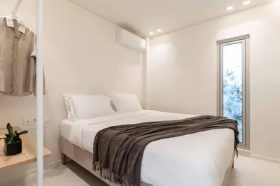 a white bedroom with a bed and a window at 2BD Boho Sea View Apartment by The Olon in Vari