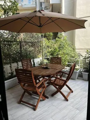a wooden table and chairs with an umbrella on a patio at Olivia Luxury Apartment Palio Faliro in Athens