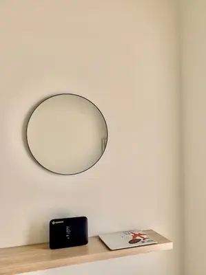 a circular mirror hanging over a shelf with a book at Feels like home (Vari) in Vari