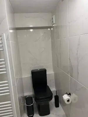 a bathroom with a black toilet and white tiles at Riviera-MelRod-Athens in Athens