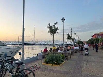 a group of people sitting at tables near a marina at Riviera-MelRod-Athens in Athens