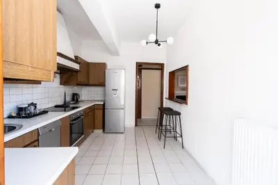a kitchen with a refrigerator and chairs in it at AIOLOS LUXURY alimos center Suite II near the sea in Athens