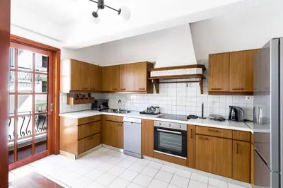 a kitchen with wooden cabinets and a large window at AIOLOS LUXURY alimos center Suite II near the sea in Athens