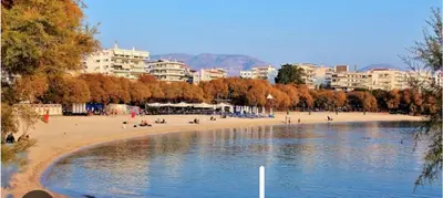 a group of people on a beach with buildings in the background at AIOLOS COZY alimos center APARTMENT near the sea in Athens