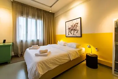 a bedroom with a large white bed with yellow walls at Artistic Spacious Studio Apartment next to metro Monastiraki in Athens