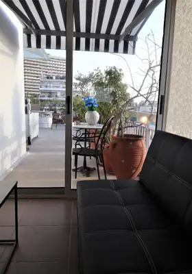 a living room with a couch and a table on a balcony at Stunning view private terrace studio @Panormou Metro. in Athens