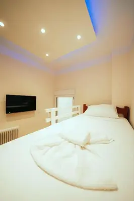 a bedroom with a white bed with a tv on the wall at The Sandbox in Athens