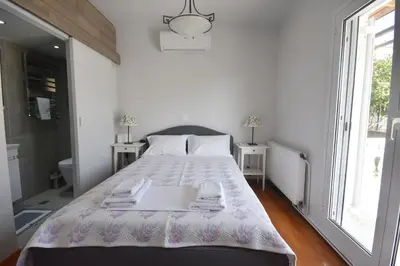 a white bedroom with a bed with a laptop on it at VillaVita Modern 3BR,Garden & BBQ, Walk to Beach in Kalívia Thorikoú