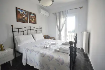 a bedroom with a bed with white sheets and a window at VillaVita Modern 3BR,Garden & BBQ, Walk to Beach in Kalívia Thorikoú
