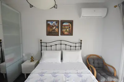 a bedroom with a bed and a chair at VillaVita Modern 3BR,Garden & BBQ, Walk to Beach in Kalívia Thorikoú