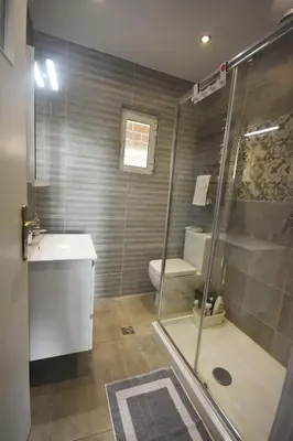 a bathroom with a shower and a toilet and a sink at VillaVita Modern 3BR,Garden & BBQ, Walk to Beach in Kalívia Thorikoú