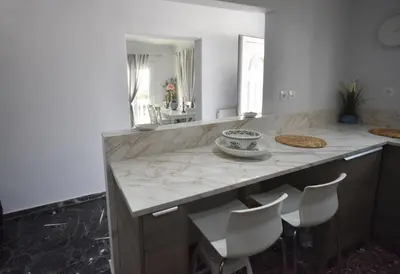 a kitchen with a counter with chairs and a mirror at VillaVita Modern 3BR,Garden & BBQ, Walk to Beach in Kalívia Thorikoú