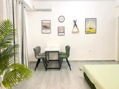 a room with a table and two chairs and a clock at Uoohome7 garden green and navy in Athens